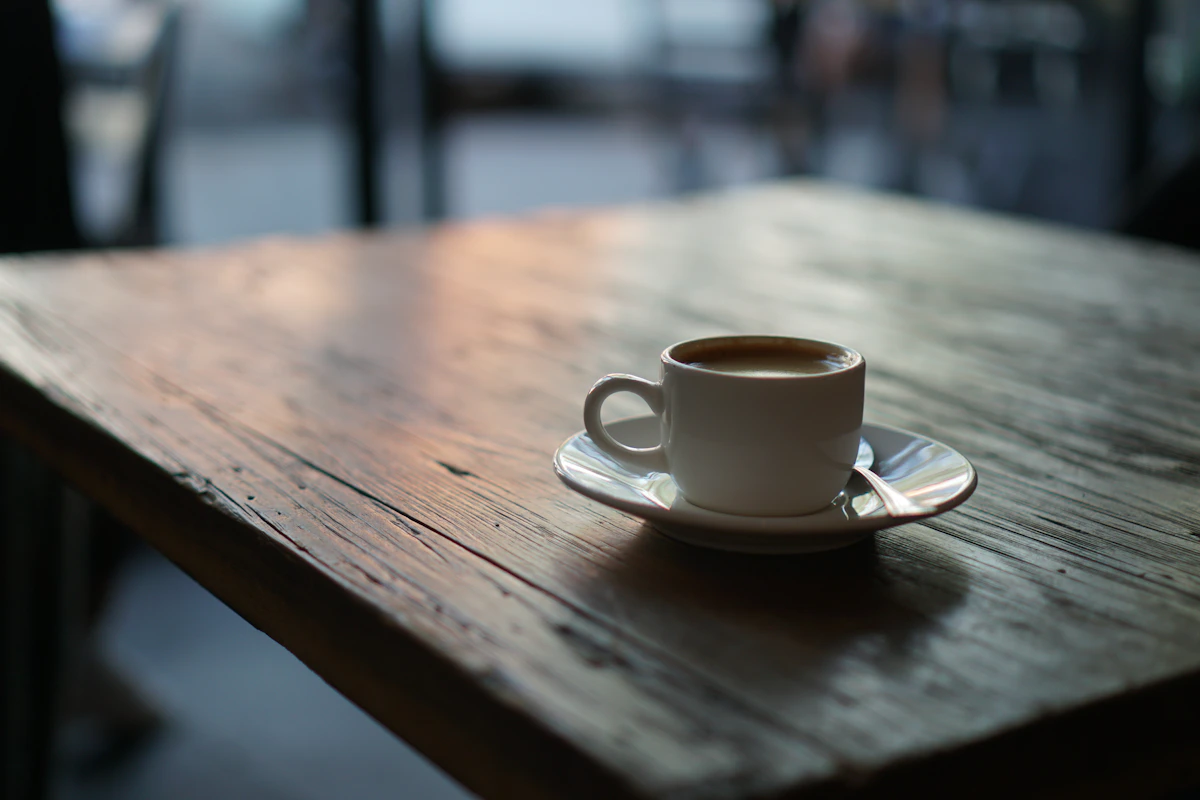 A cup of coffee and saucer on a wooden table